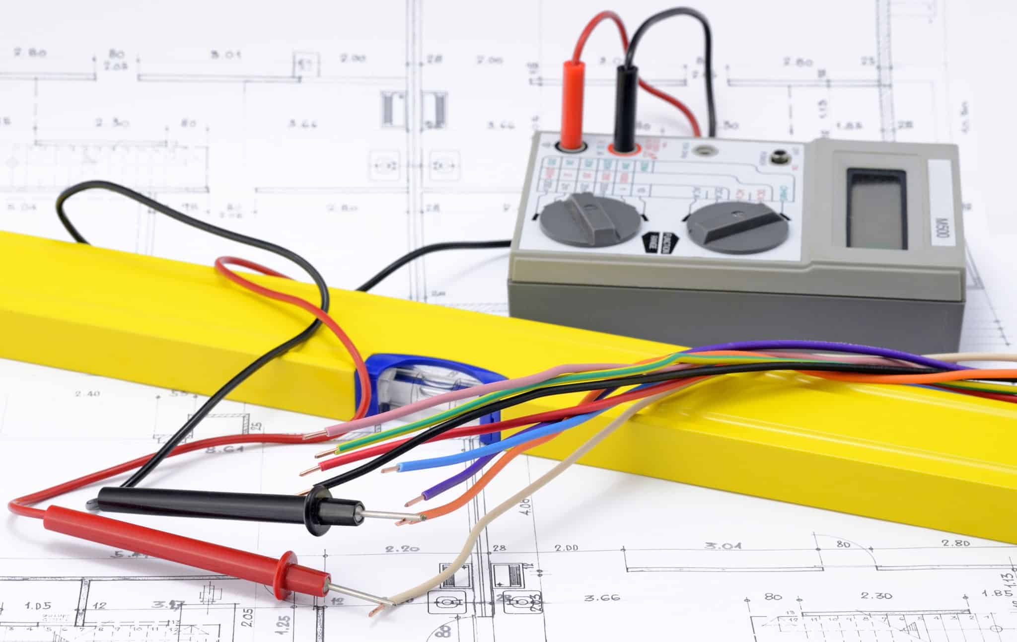 Kabel und eine Gelbe Wasserwaage liegen auf einem Plan